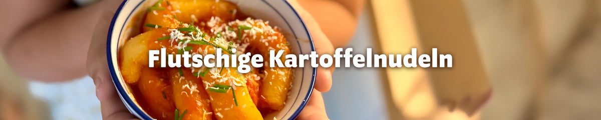 Schüssel mit selbstgemachten Kartoffelnudeln in Tomatensoße, garniert mit Parmesan und Schnittlauch