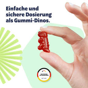 Roter Vitasauri Kids Mix Gummi-Dino zwischen zwei Fingern – einfache Dosierung des Multivitamins für Kinder